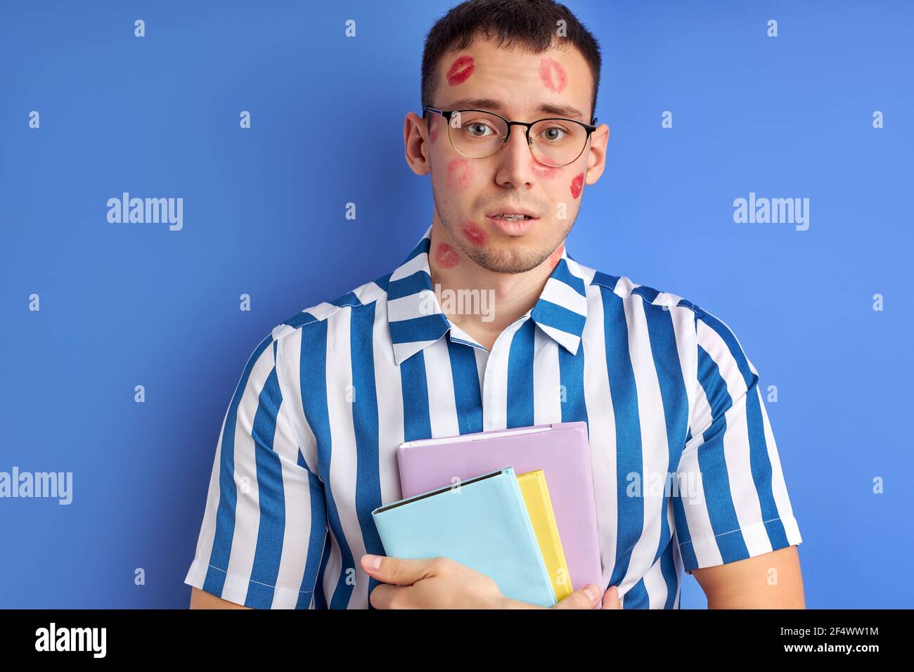 jeune wonk avec des empreintes de baiser tenant des livres isolés sur fond bleu, ayant perdu la vue. personnes, amour, émotions concept Banque D'Images