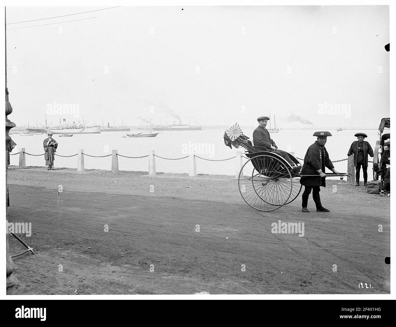 Kobe. Touriste à Riksha avec chauffeur natif contre le port avec des bateaux et des bateaux de luxe Banque D'Images