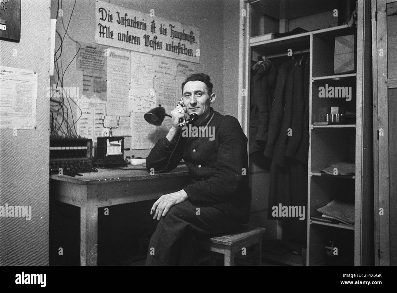 Deuxième Guerre mondiale. Pays-Bas sous équipage allemand. Telephoneist de la Wehrmacht allemande dans une salle de service sous un transparent avec l'inscription "l'infanterie est l'arme principale. Soutenez toutes les autres armes. » (Bien à la Haye) Banque D'Images