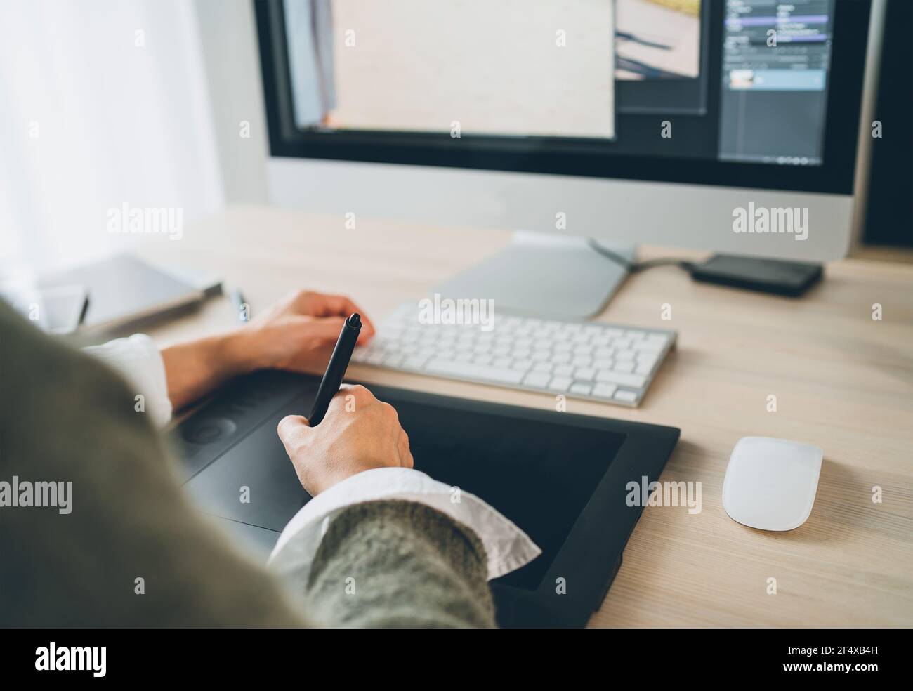 Mains de femmes utilisant une tablette graphique avec stylet et un clavier d'ordinateur moderne pour dessiner des œuvres d'art. Design graphique, arts numériques ou travail indépendant Banque D'Images