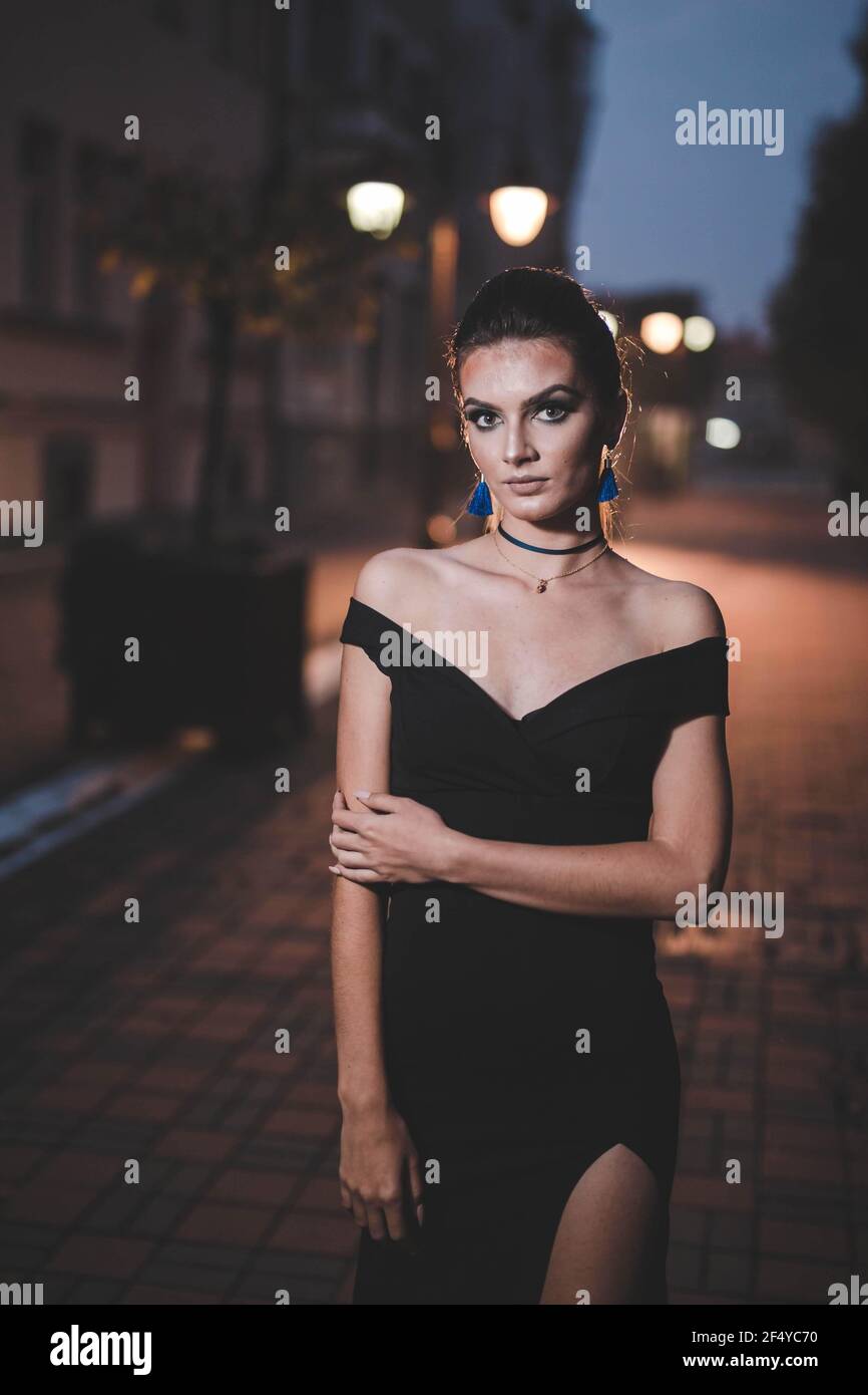 Jolie femme de race blanche bosniaque portant une robe noire contre le  bokeh éclaire l'arrière-plan Photo Stock - Alamy