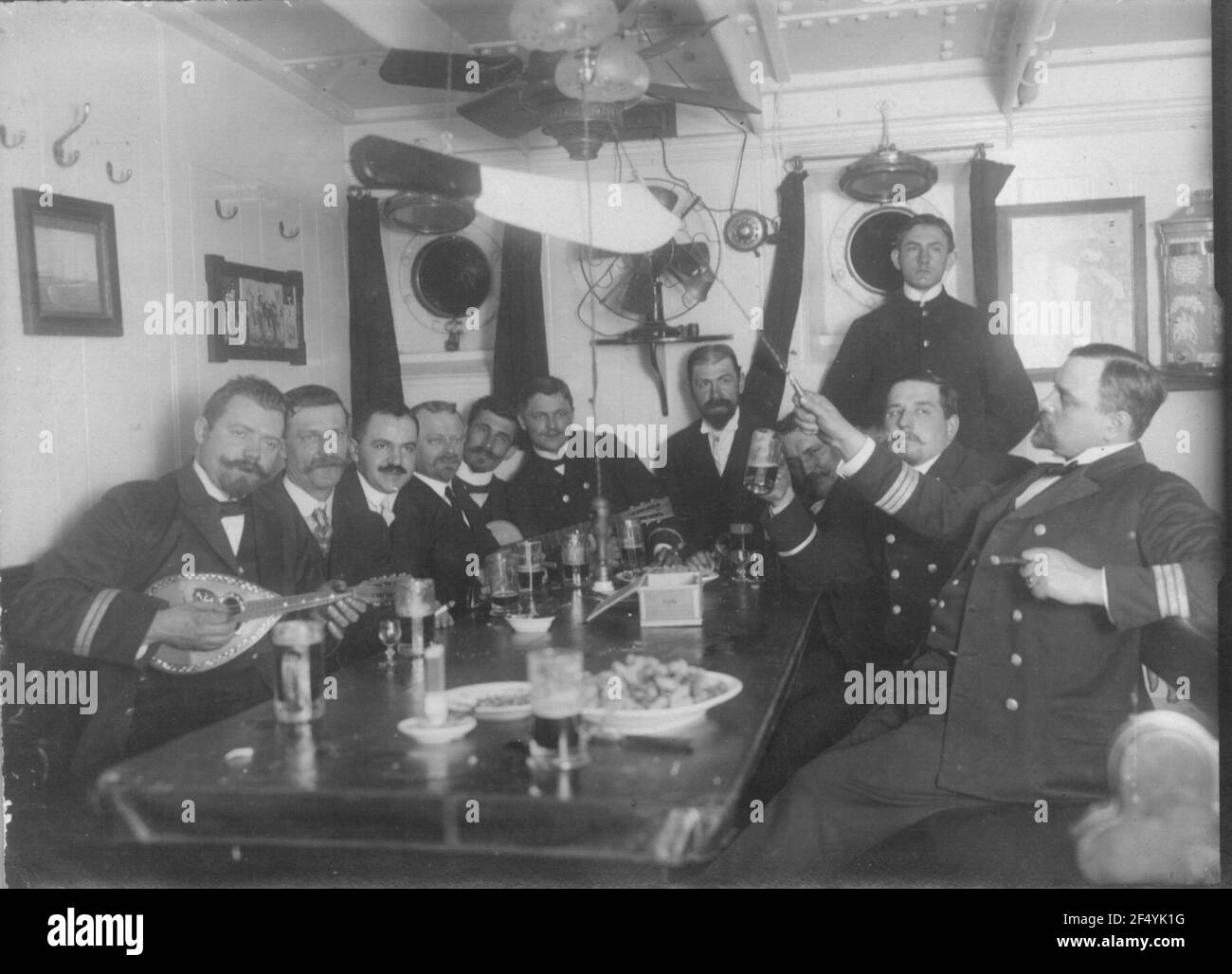 Croisières de la ligne Hambourg-Amérique, vers 1910. Groupe d'hommes avec membres d'équipage et capitaine ? un bateau à vapeur en haute mer pour les passagers en réunion à la table de bière dans une salle de club Banque D'Images