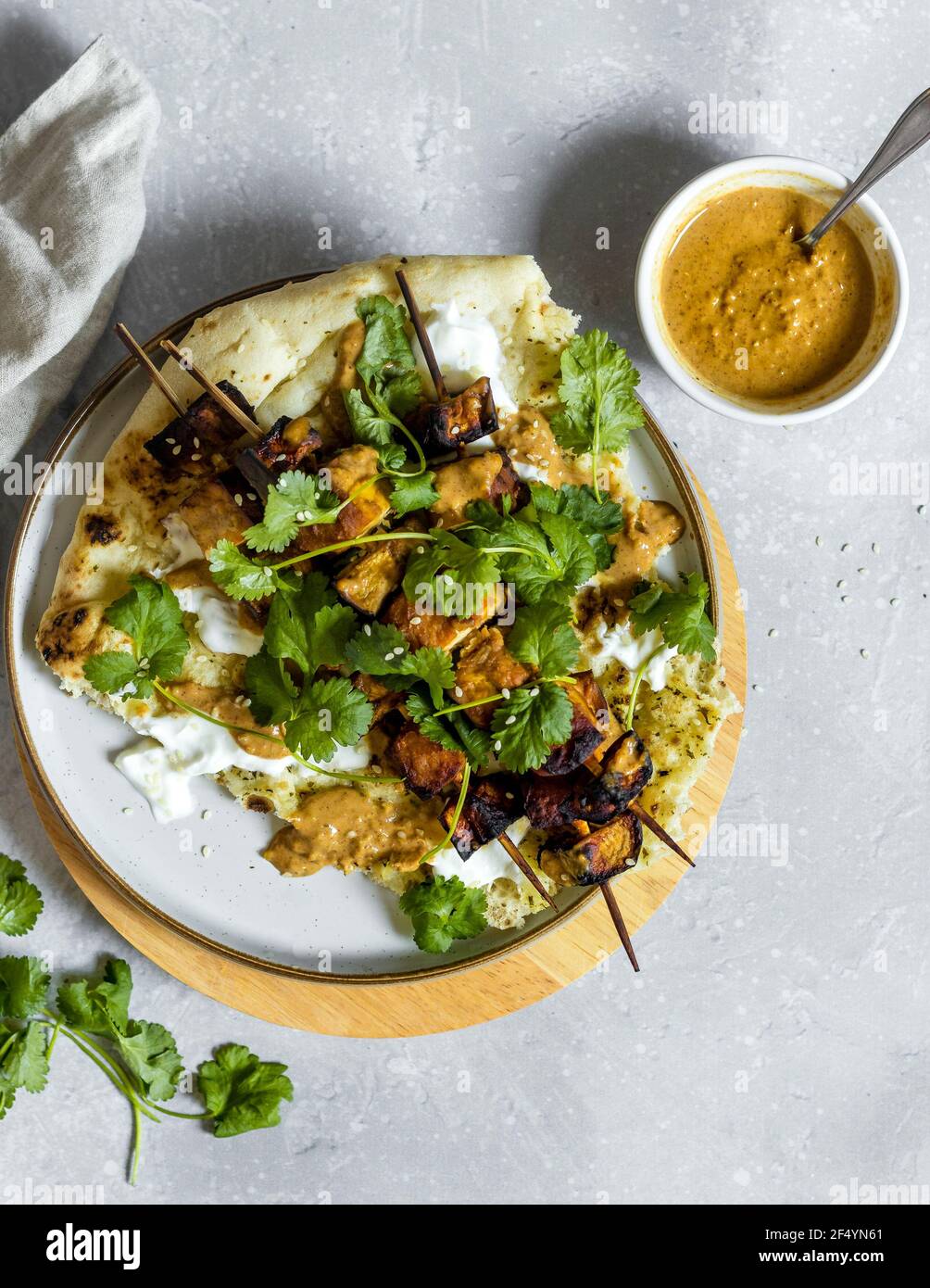 Dîner/déjeuner à Fakeaway vegan - pain naan, yaourt végétalien et aubergines et tofu faits maison dans un glaçage miso, garni de graines de sésame et de coriandre Banque D'Images