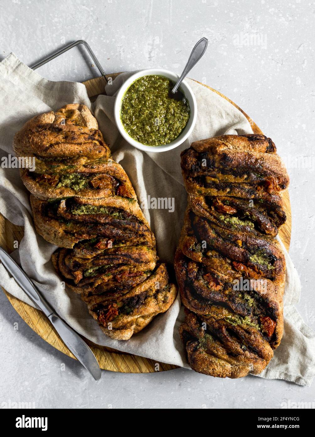 Fraîchement sortis du four, pains tordus vegan faits maison avec pesto aux épinards et tomates séchées. Pique-nique, déjeuner ou hors-d'œuvre parfaits. Banque D'Images