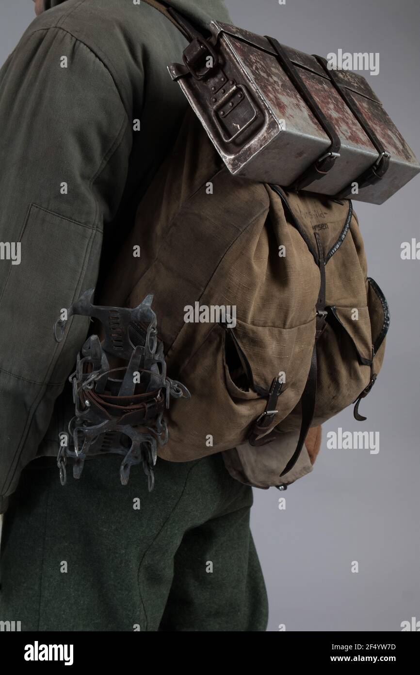 acteur homme dans l'ancien uniforme de montagne d'hiver près de la MG 42 mitrailleuse pendant la deuxième Guerre mondiale pose sur fond gris Banque D'Images