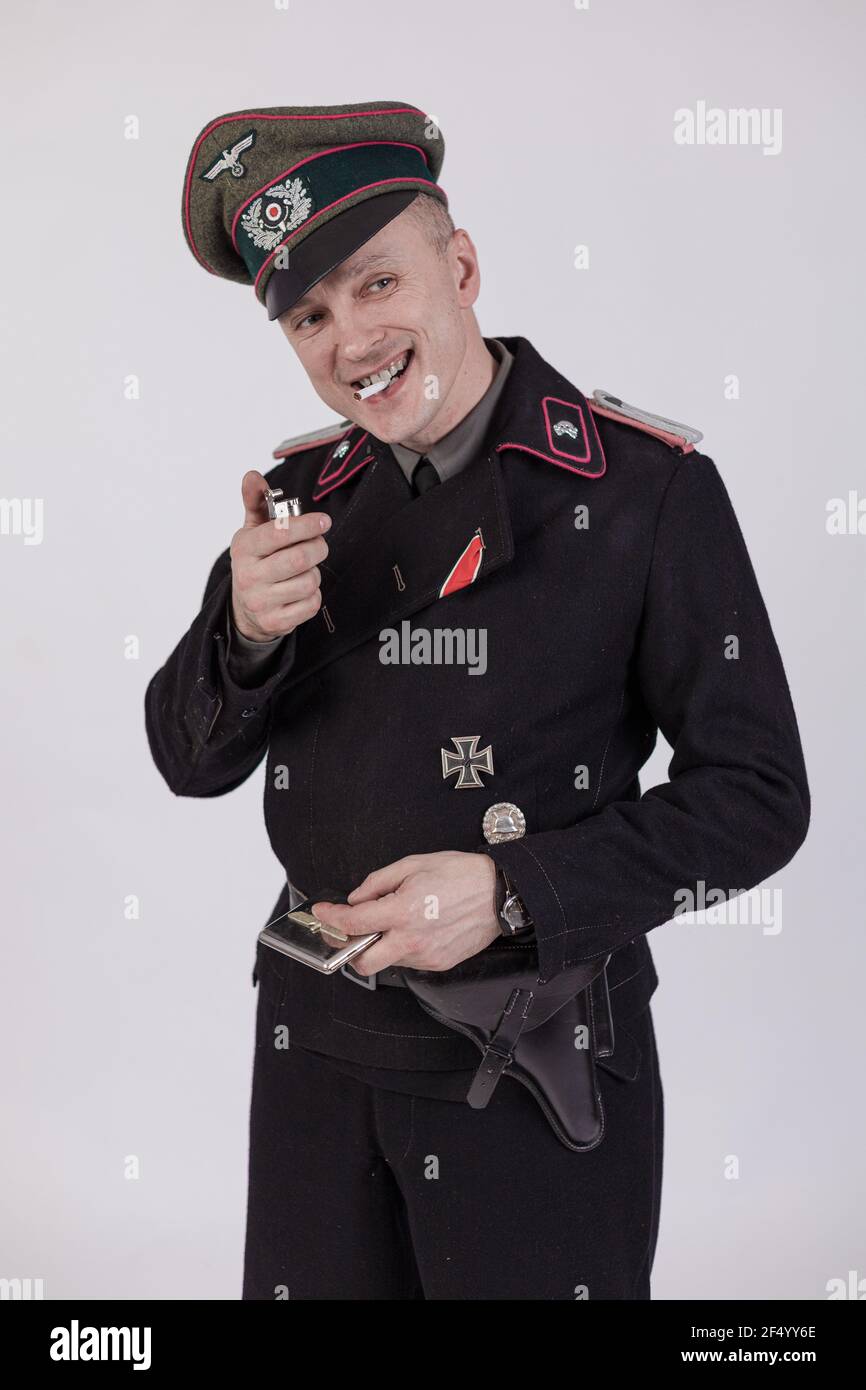 Acteur masculin réacteur dans l'uniforme militaire historique de char comme un officier de l'armée allemande pendant la Seconde Guerre mondiale à fume une cigarette sur un backgrou blanc Banque D'Images