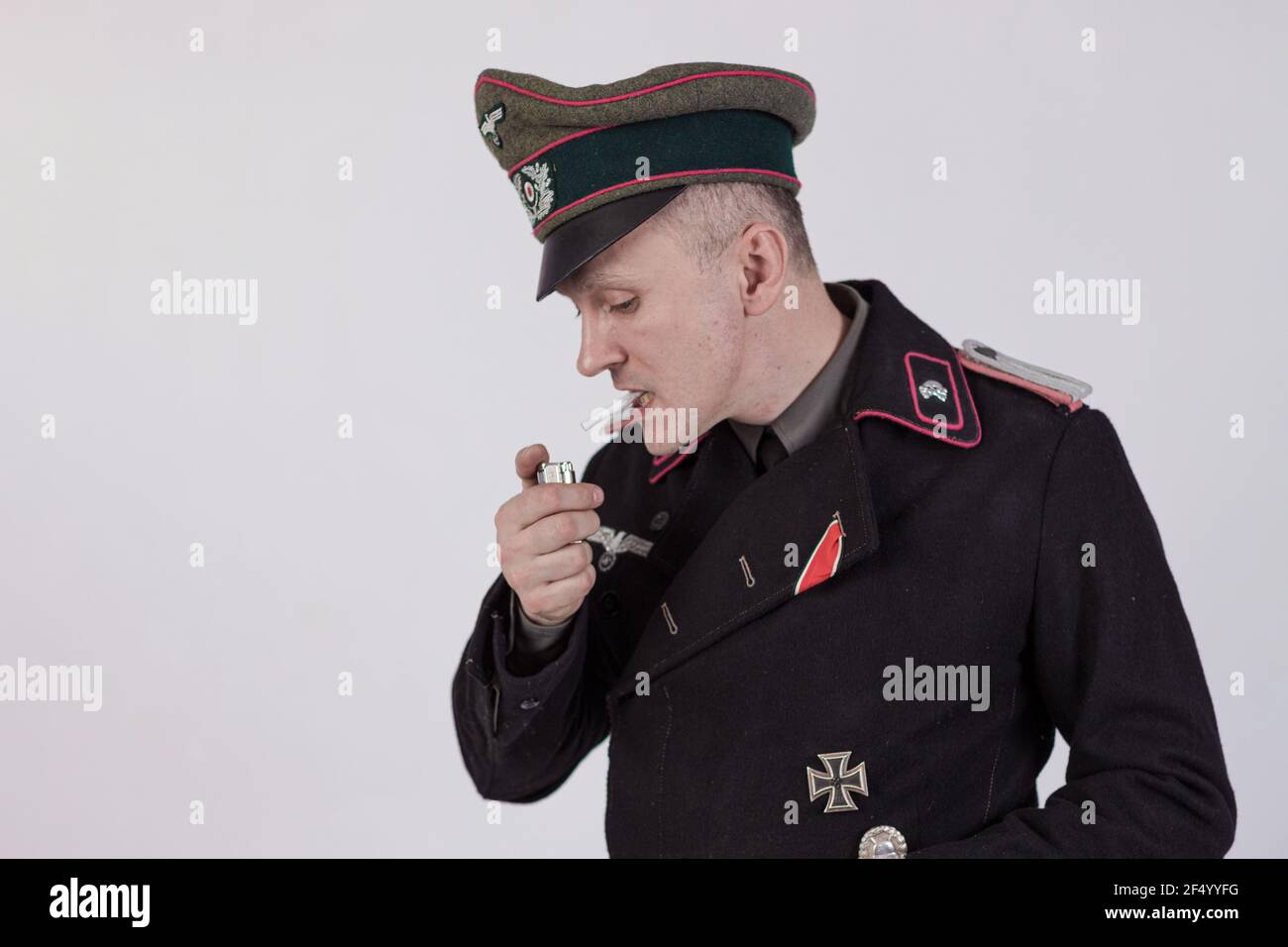 Acteur masculin réacteur dans l'uniforme militaire historique de char comme un officier de l'armée allemande pendant la Seconde Guerre mondiale à fume une cigarette sur un backgrou blanc Banque D'Images