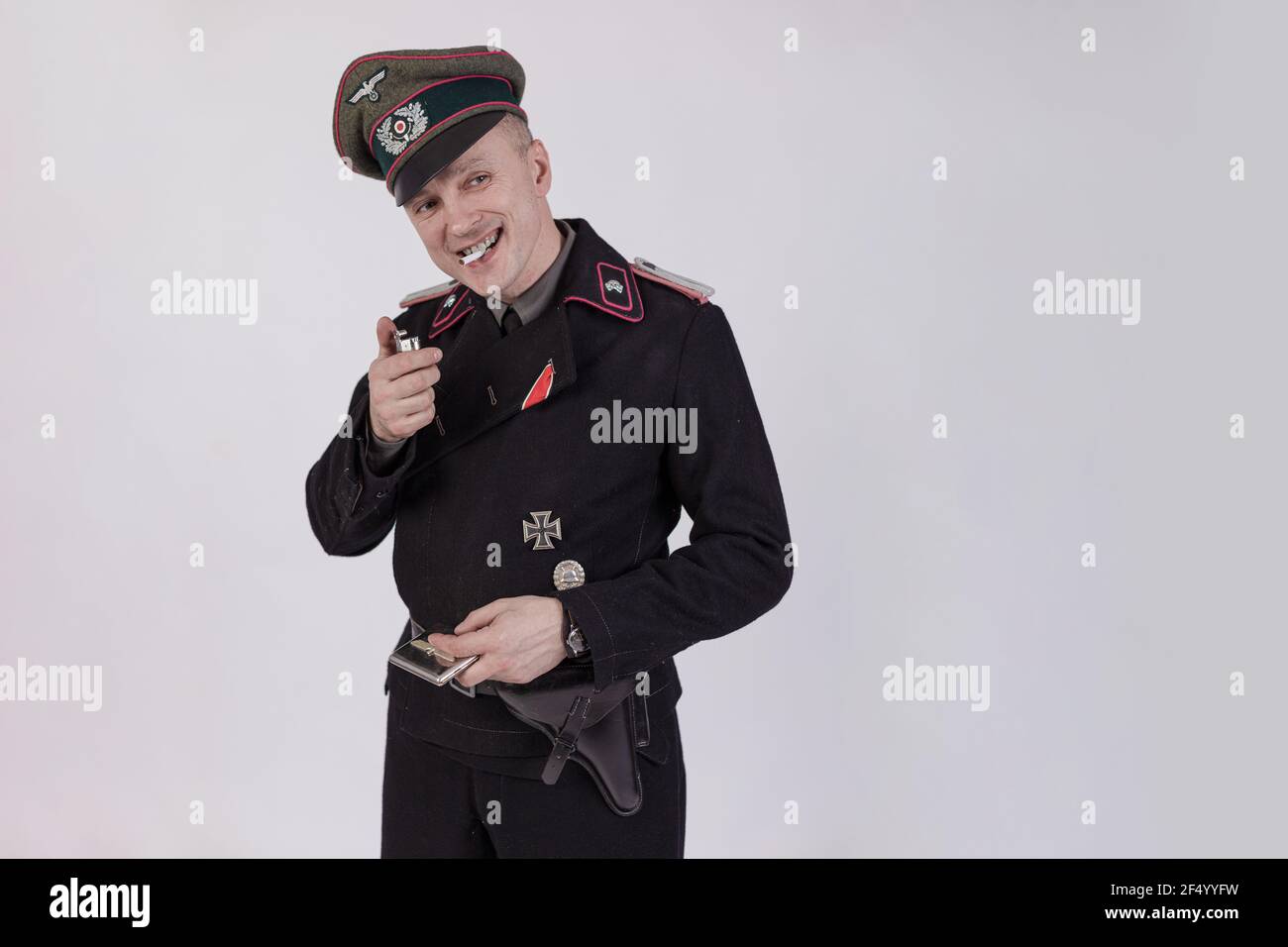 Acteur masculin réacteur dans l'uniforme militaire historique de char comme un officier de l'armée allemande pendant la Seconde Guerre mondiale à fume une cigarette sur un backgrou blanc Banque D'Images