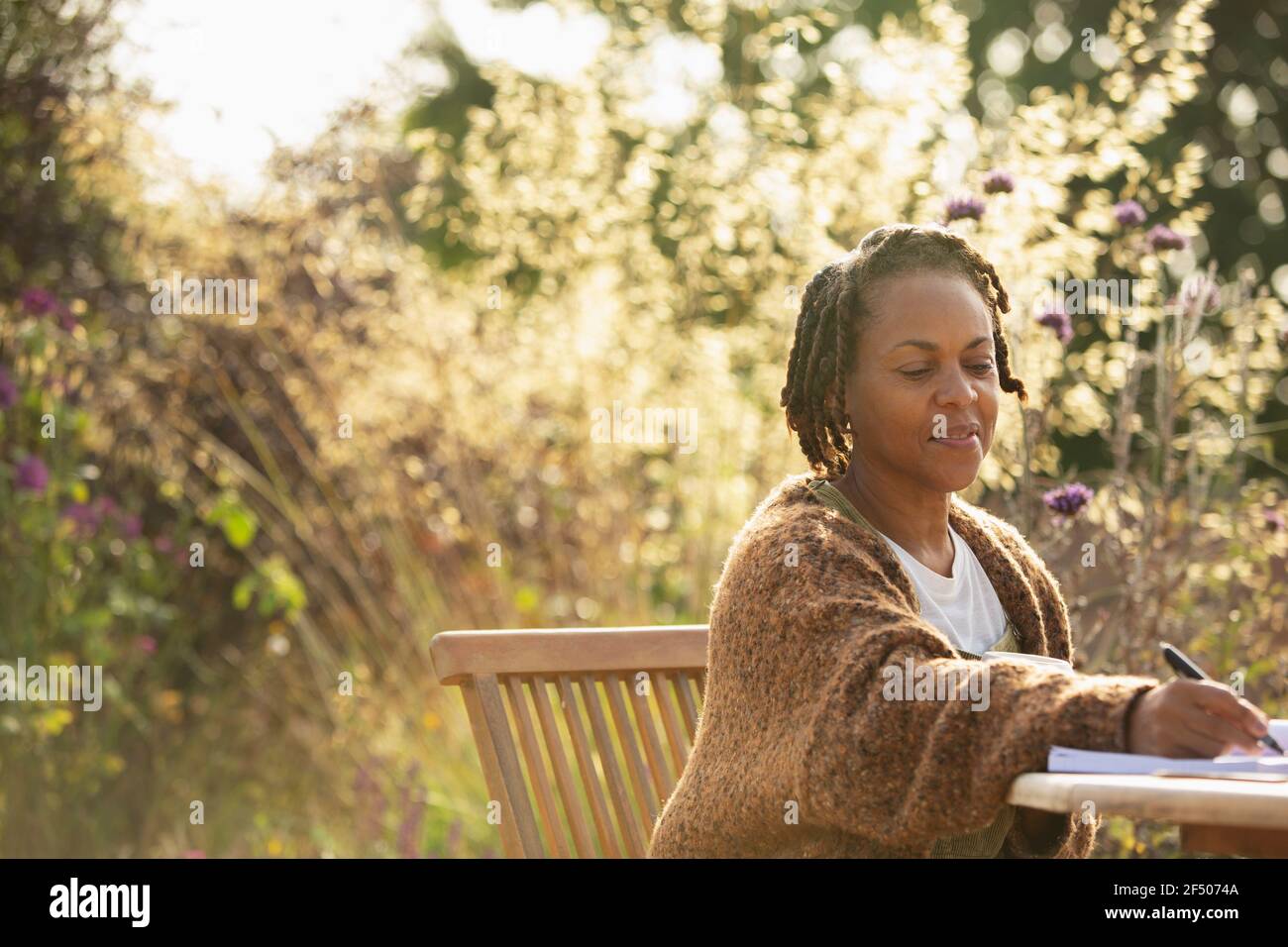 Femme travaillant à une table sur le patio du jardin Banque D'Images