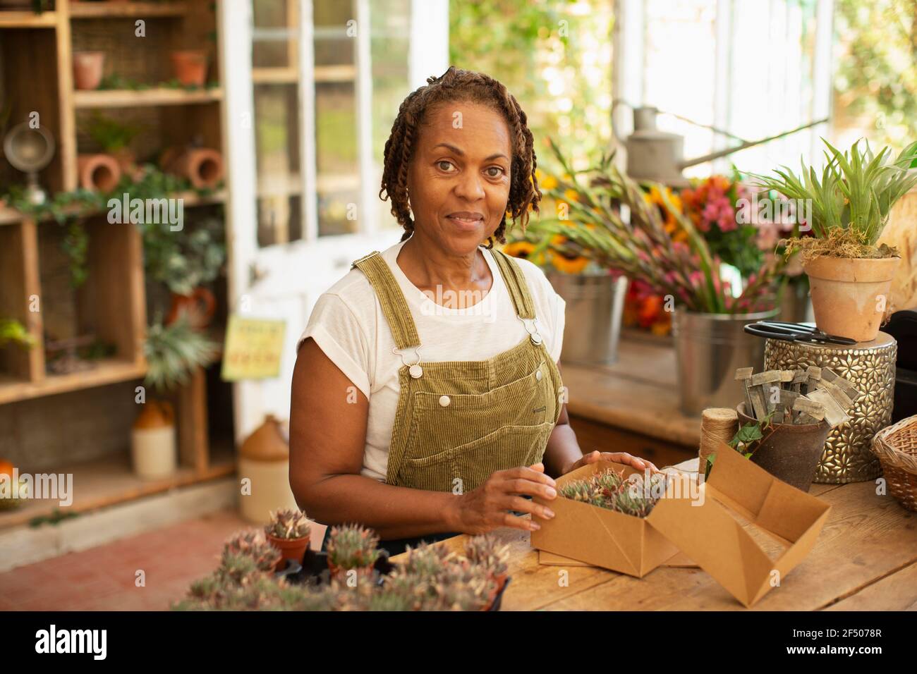 Portrait femelle fleuriste boxe de minuscules plantes succulentes dans la boutique de jardin Banque D'Images