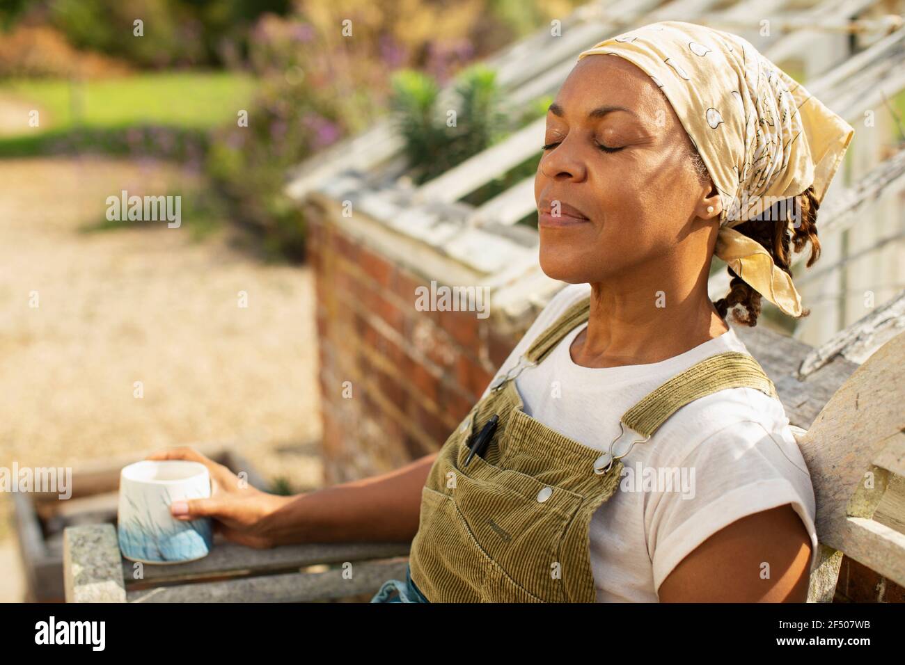 Sereine femme jardinière prenant une pause-café en pleine lumière du soleil Banque D'Images