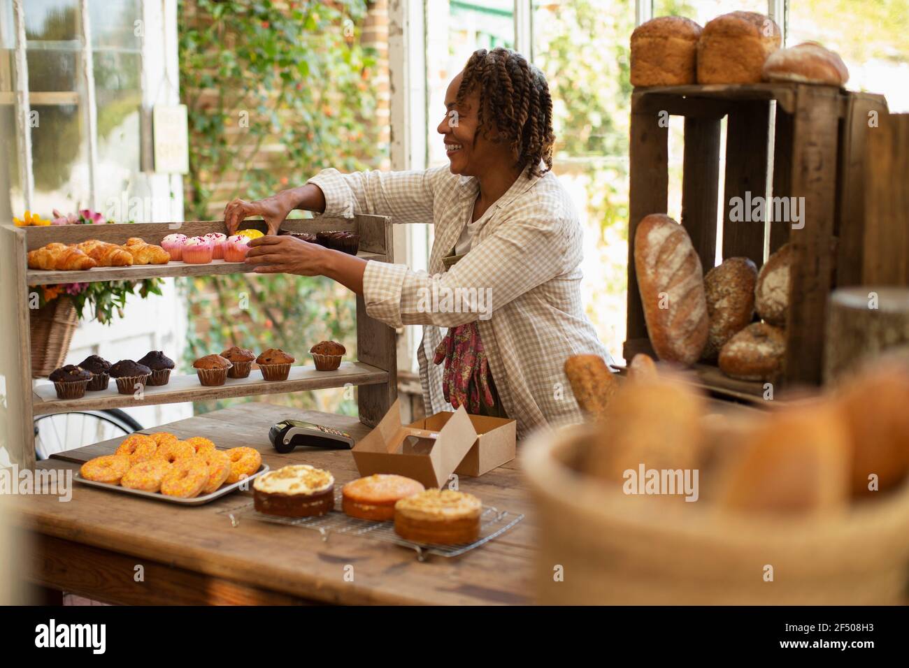 Boulanger femme organisant une exposition de pâtisserie dans le magasin Banque D'Images