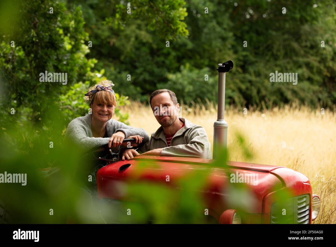 Portrait heureux couple au tracteur dans le verger Banque D'Images
