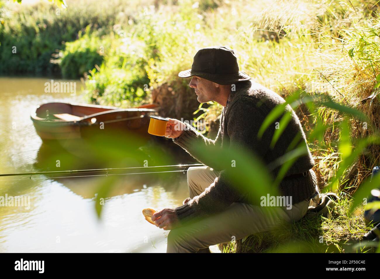 L'homme pêche à la mouche et boire du café à la rivière ensoleillée Banque D'Images