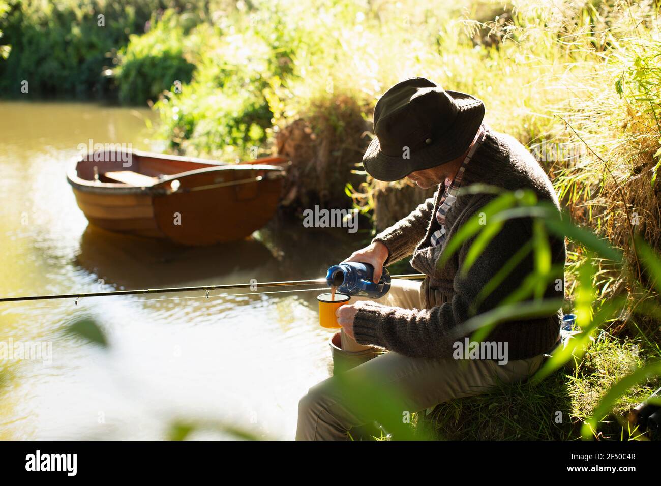 L'homme pêche à la mouche et le café versant à la rivière ensoleillée Banque D'Images