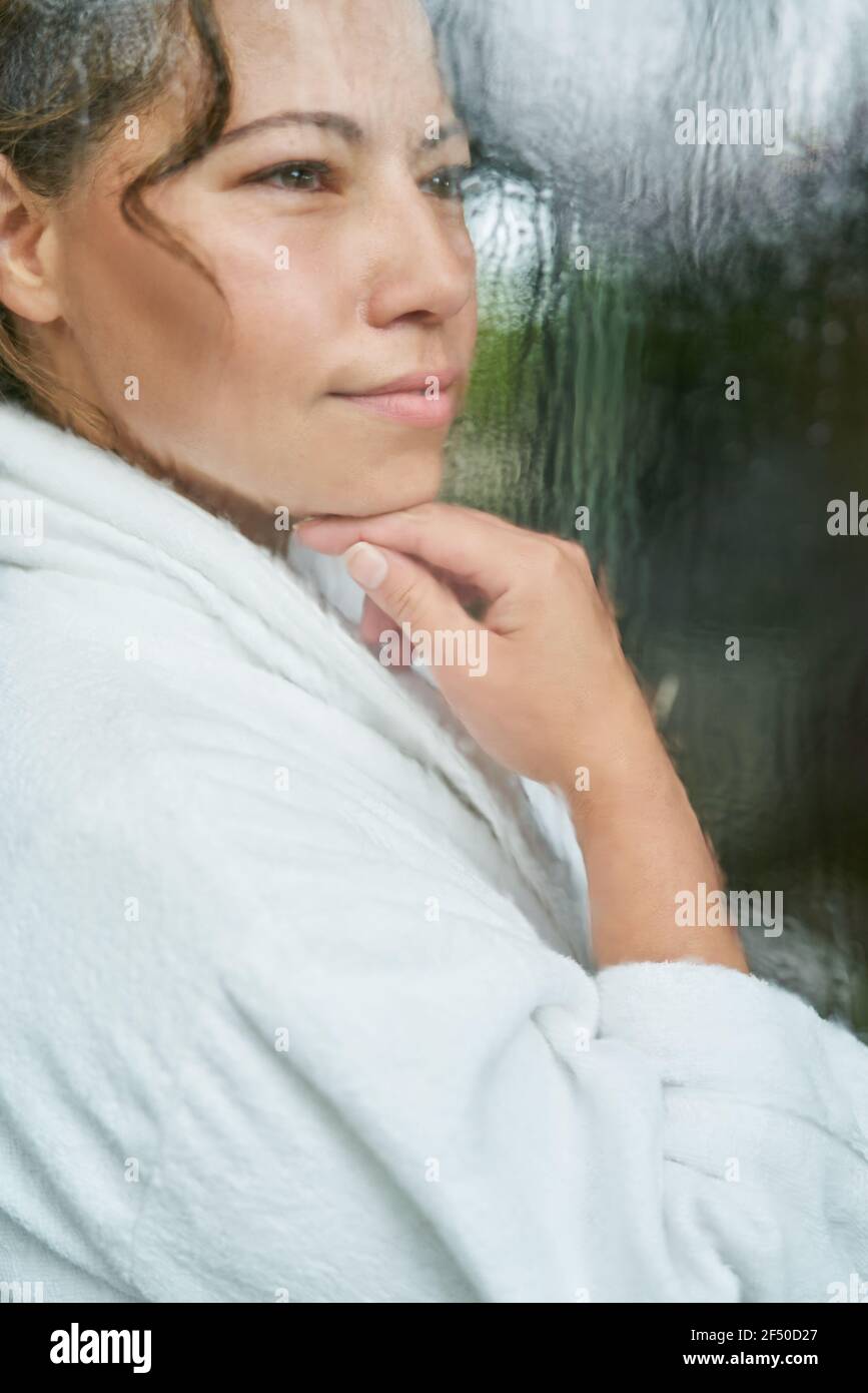 Belle femme en peignoir à la fenêtre de pluie Banque D'Images