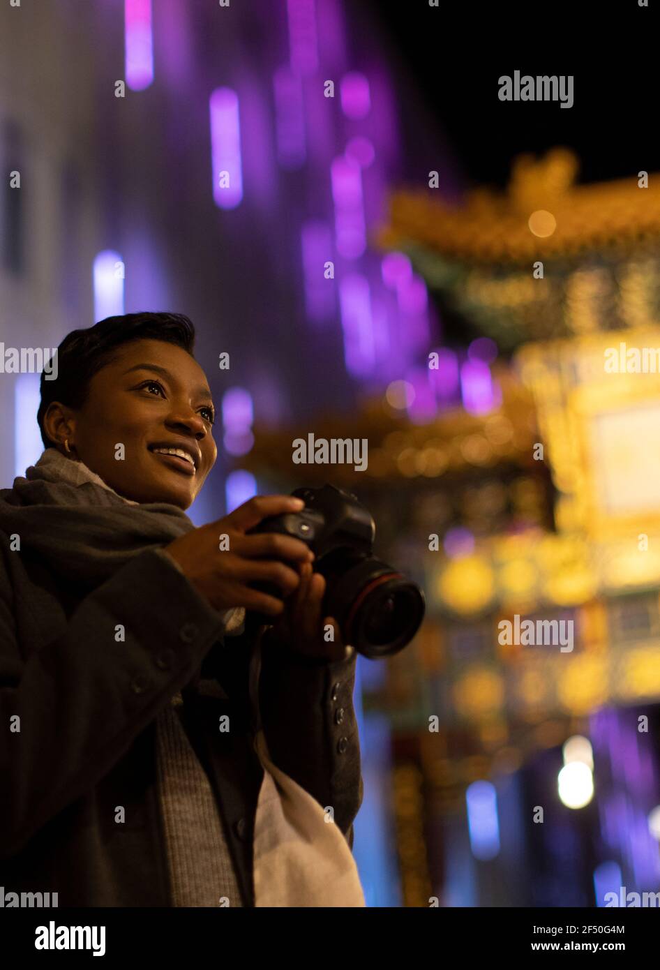 Jeune femme heureuse avec appareil photo numérique à Chinatown Gate, Londres, Royaume-Uni Banque D'Images