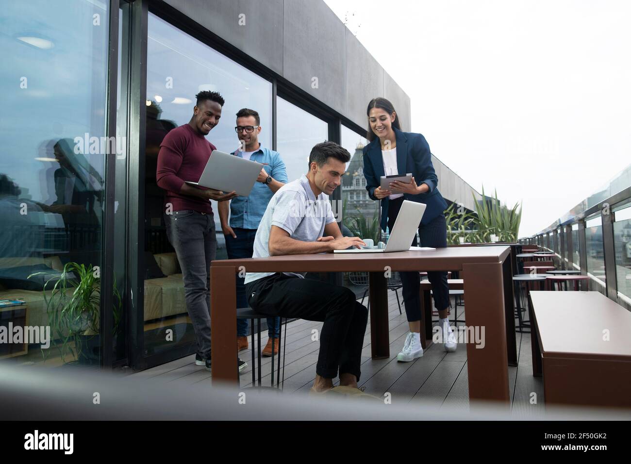 Professionnels travaillant avec des ordinateurs portables et une tablette numérique sur un balcon Banque D'Images