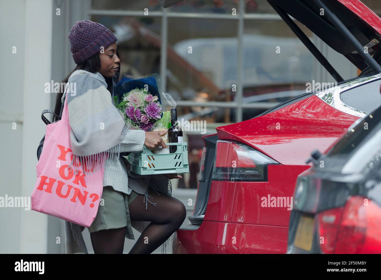 Une jeune femme charge des produits d'épicerie dans le hayon de la voiture à l'extérieur du magasin Banque D'Images