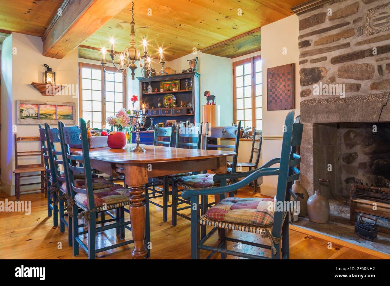 Table à manger en pin avec deux fauteuils capitaine et six chaises hautes à  l'arrière, buffet en pin antique et cheminée à bois de pierre naturelle  Photo Stock - Alamy