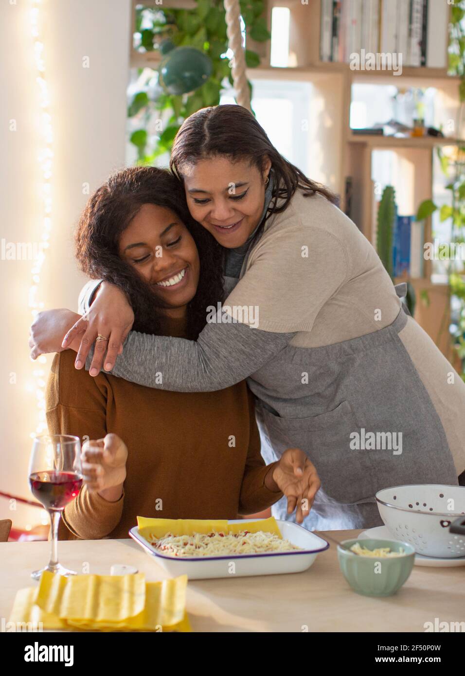 Mère et fille affectueuses qui embrasse et cuisent des lasagnes Banque D'Images