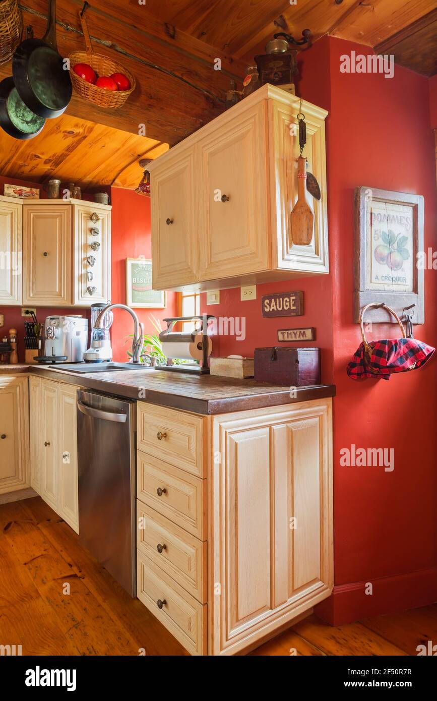 Armoires en bois de chêne peint en blanc et comptoirs en céramique nuancés aux tons de terre dans la cuisine avec planchers en bois de pin, murs peints en rouge à l'intérieur de la vieille maison Banque D'Images