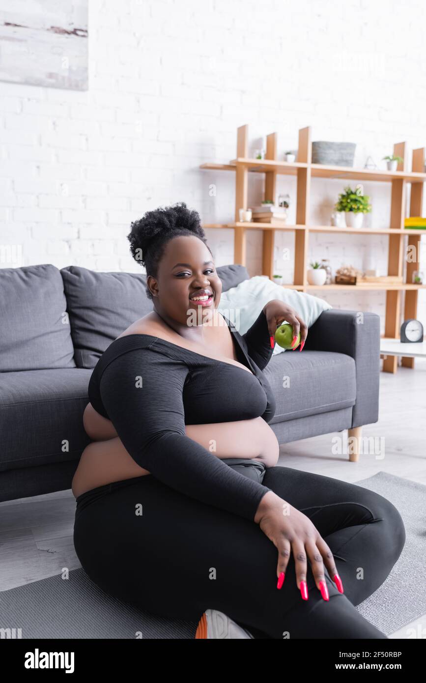 joyeux afro americain femme de taille plus dans les vetements de sport tenant vert apple Photo Stock Alamy