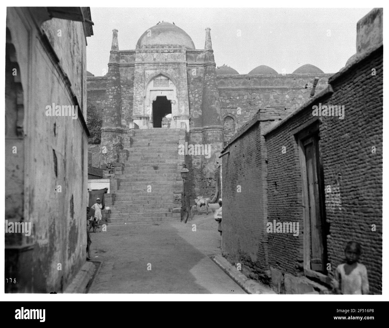 Delhi, Inde. JAMA Masjid (Masjid-i Jahan Numa, 'mosquée du vendredi') (1644-1658; Shah Jahan). Vue à travers une allée avec des bâtiments résidentiels sur un accès à la mosquée du vendredi dans l'énorme mur de forteresse avec dôme et escaliers Banque D'Images