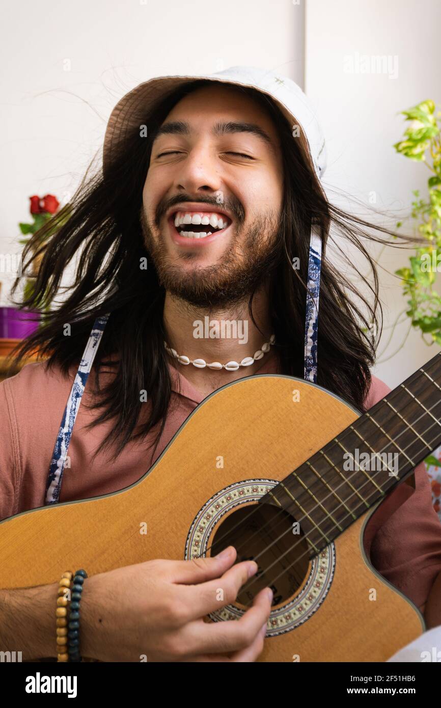 homme à poil long chantant et jouant de la guitare, homme bohème et hippie,  portant le corail comme un collier et un chapeau de seau.souriant Photo  Stock - Alamy