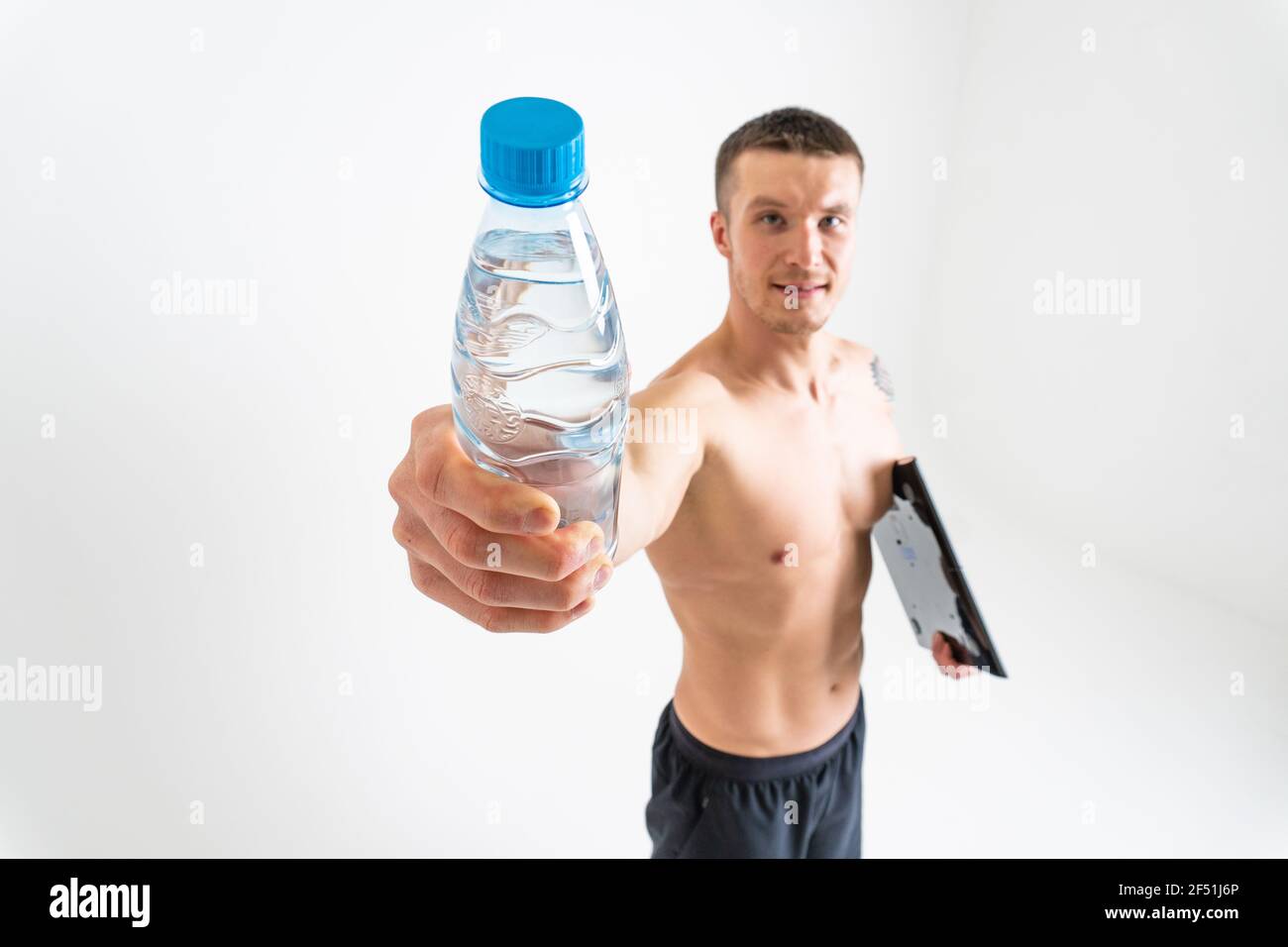 La forme physique à l'eau potable est pompée avec une serviette sur un fond blanc isolé forte santé d'entraînement, boire jeune homme personne, l'hydratation de fond. Banque D'Images