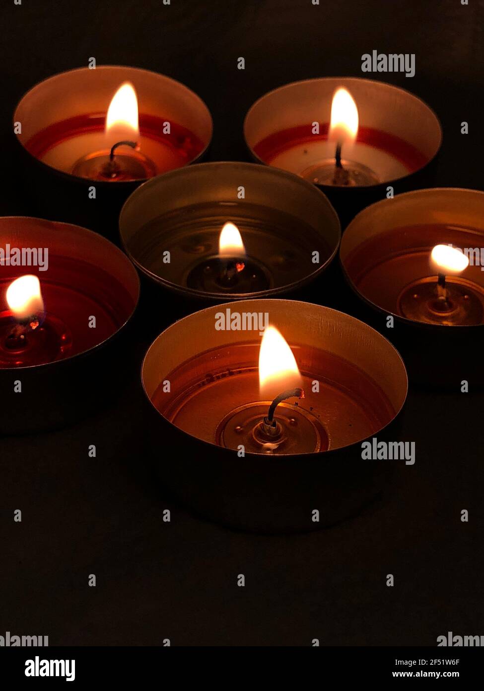 Bougies allumées - flamme. Petits radiateurs dans une pièce sombre. Quelques bougies colorées sur une table. Flamme de bougie sur fond sombre. Fête de Noël. Banque D'Images