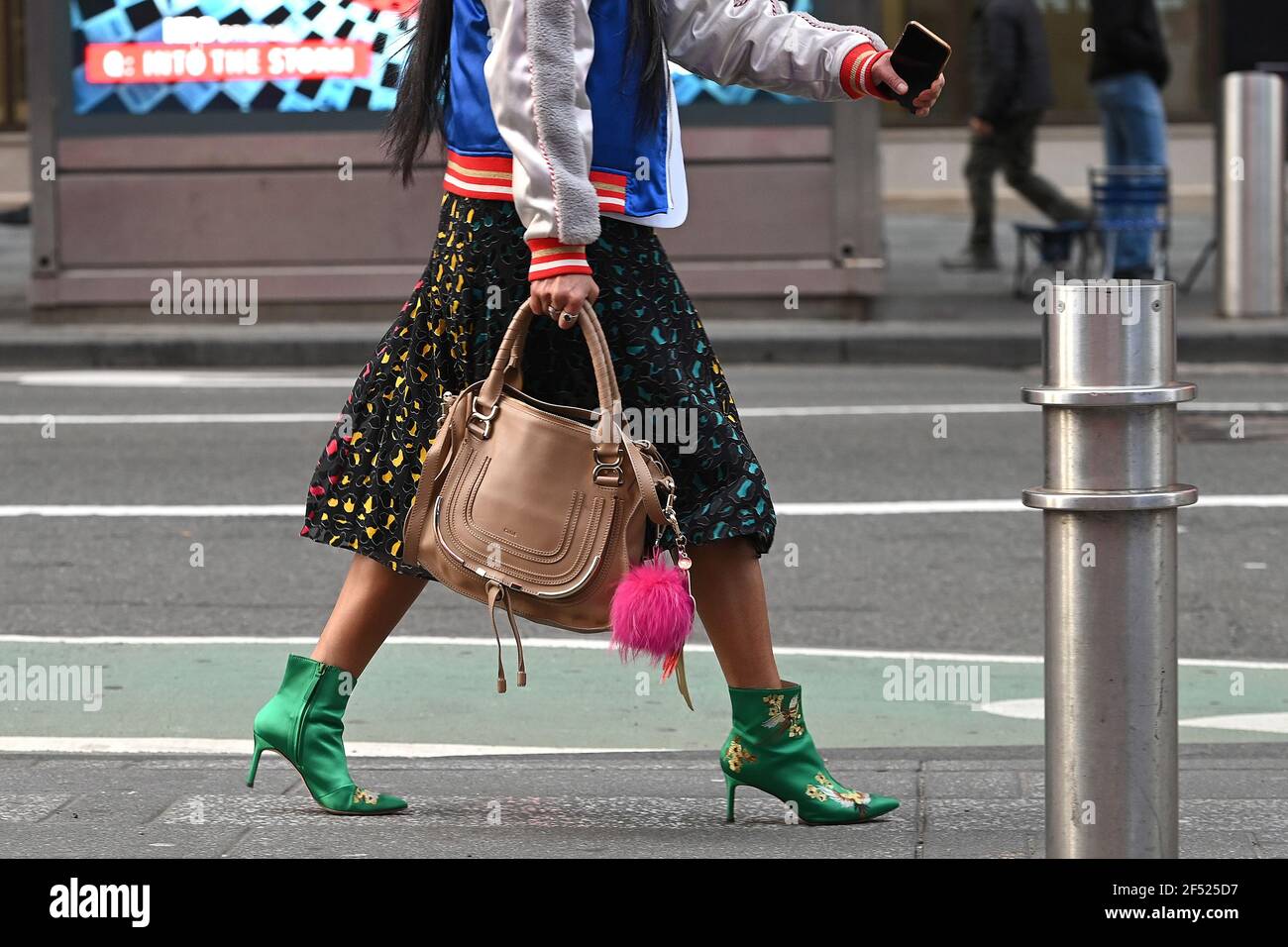Une femme portant des chaussures colorées marche à travers Times Square par  une journée chaude et ensoleillée où les températures ont atteint les  années 60 à New York, NY, le 23 mars