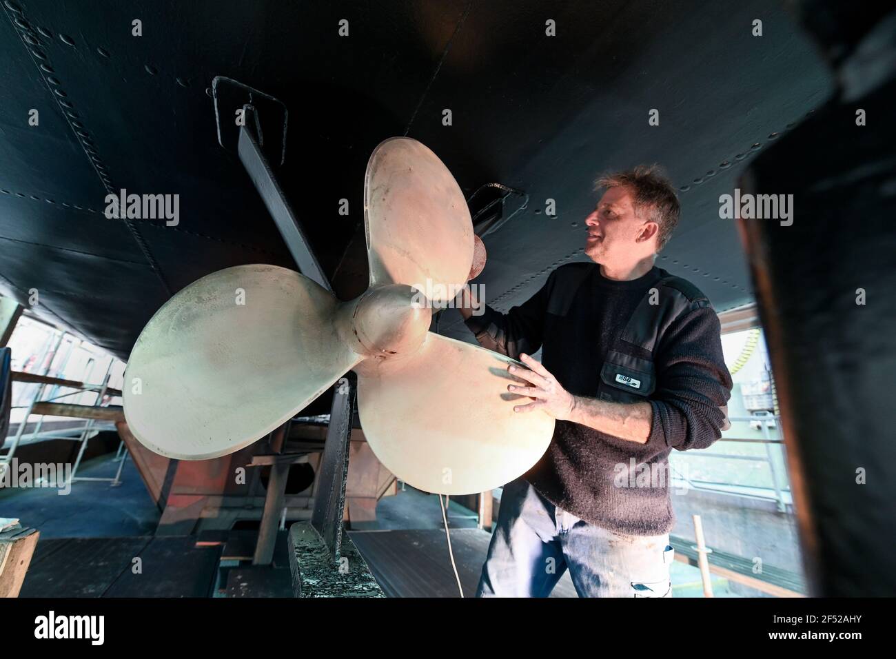 Friedrichshafen, Allemagne. 23 mars 2021. Eric Santos, employé du Bodensee Schiffsbetriebe (BSB), utilise une ponceuse orbitale pour meuler l'hélice du bateau à moteur Reichenau, qui est en préparation pour la saison au chantier naval de Friedrichshafen. (À dpa: 'Bateau d'excursion 'Reichenau' à faire dans le chantier naval') Credit: Felix Kästle/dpa/Alay Live News Banque D'Images
