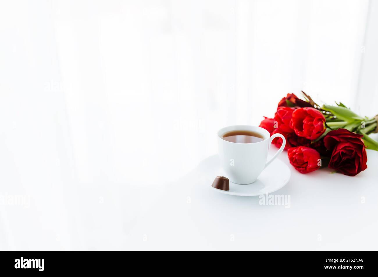 Bouquete de tulipes rouges sur table, tasse de café blanche. Concept de carte de vœux pour la fête des mères, la fête internationale des femmes ou la Saint Valentin concept, birda Banque D'Images