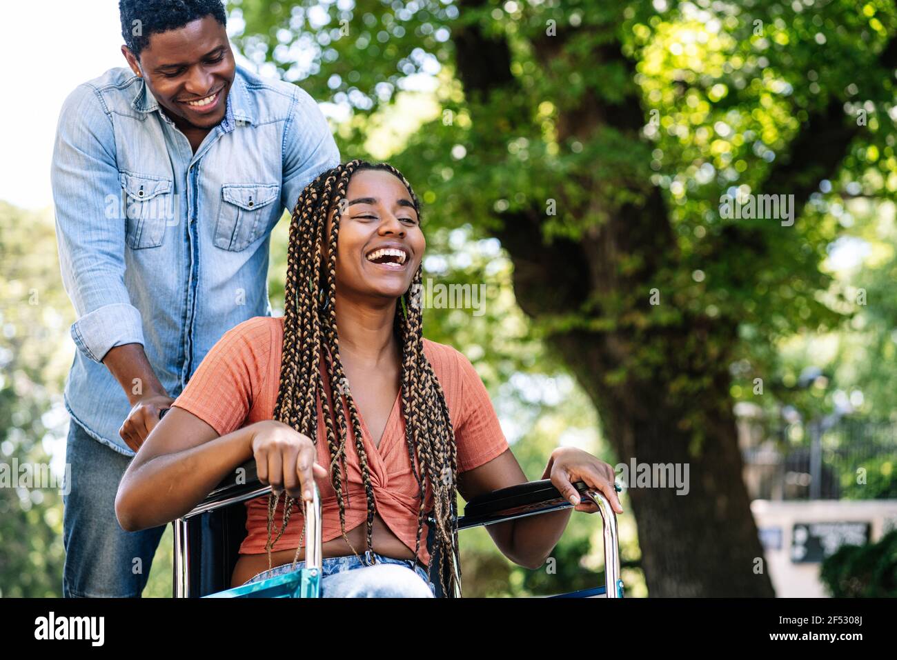 Femme en fauteuil roulant en train de marcher avec son petit ami. Banque D'Images