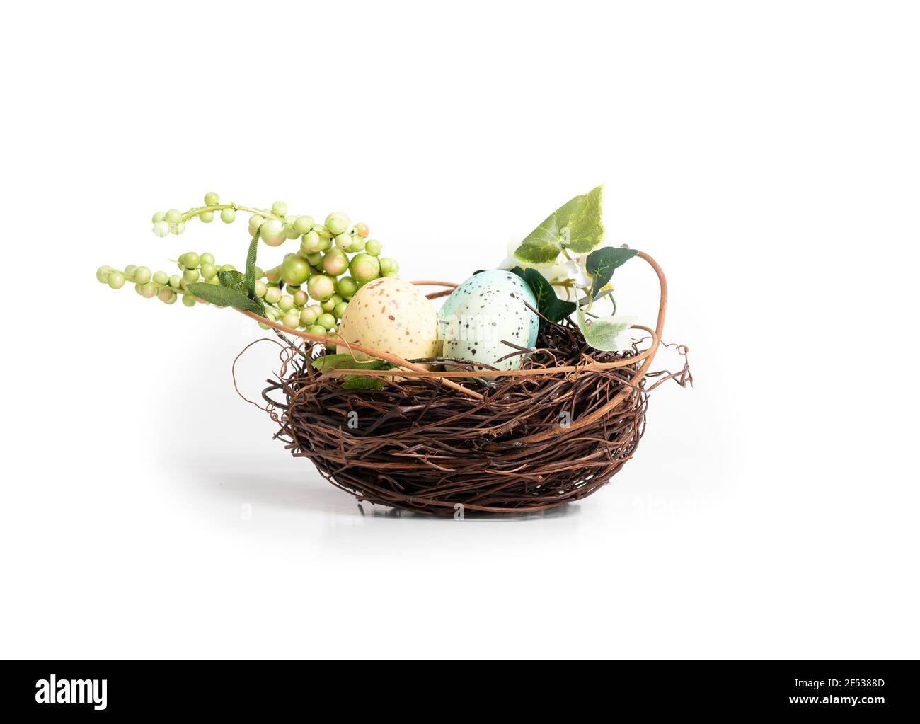 Nid d'oiseau avec œufs de Pâques et verdure artificielle. Décoration de table ou de fête de Pâques. Les petits oiseaux nichent avec des brindilles. Pois bleu et jaune doux Banque D'Images