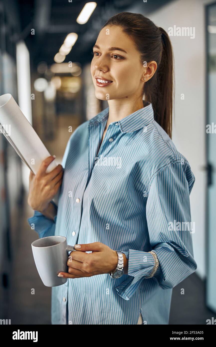 Rapporteur pour avis pensif tenant d'une main un plan de construction roulé Banque D'Images