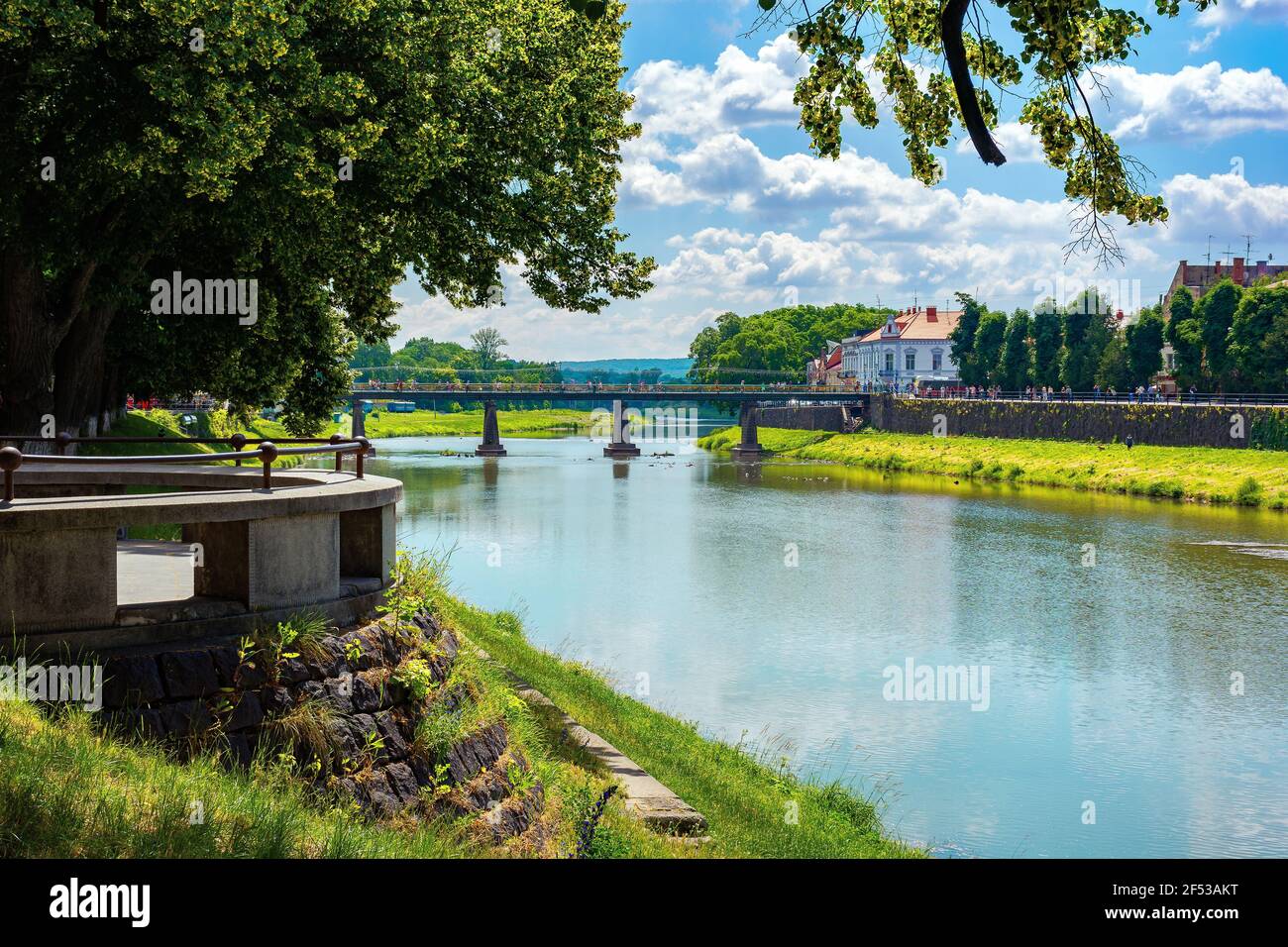 rive de la rivière uzh. magnifique paysage urbain en été. vue de dessous l'ombre d'un arbre de linden branches. pont au loin Banque D'Images