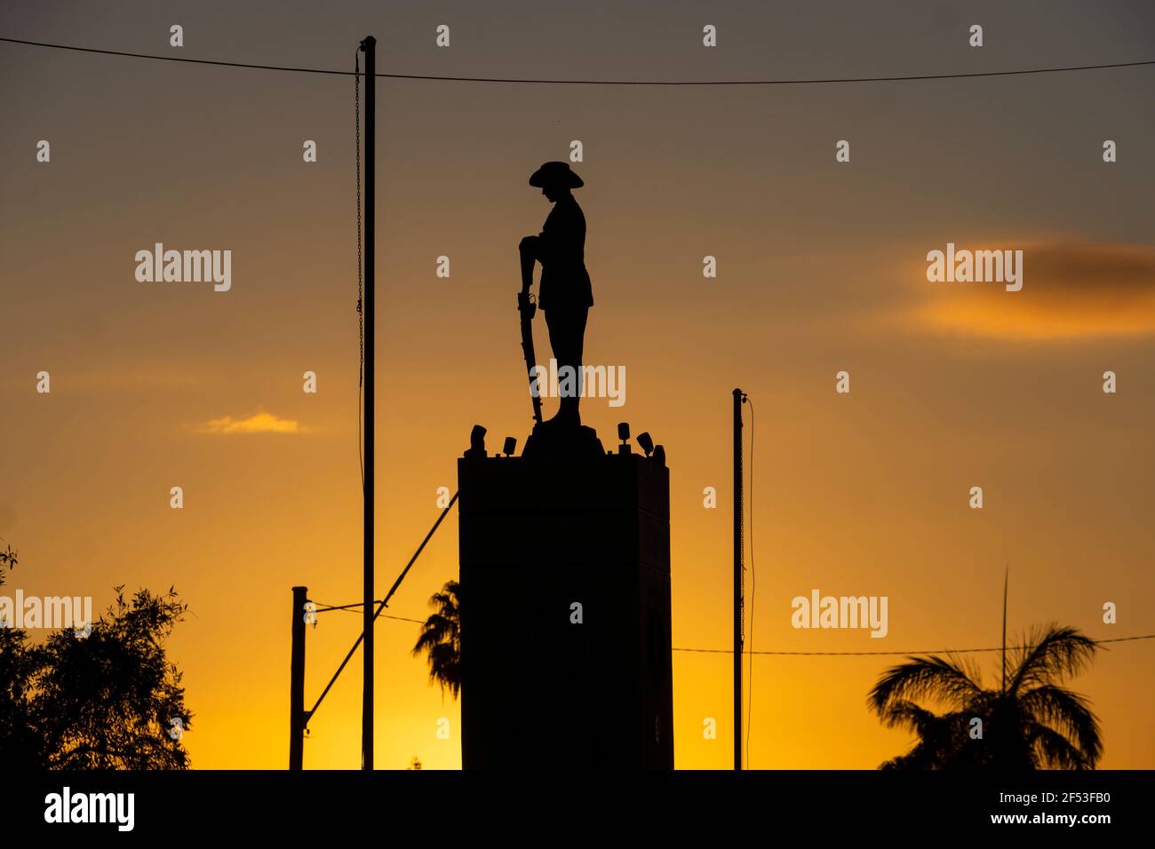 Mémorial de guerre avec un soldat et une carabine inversée à Charters Towers, Queensland, Australie, silhoueté contre un lever de soleil doré. Banque D'Images