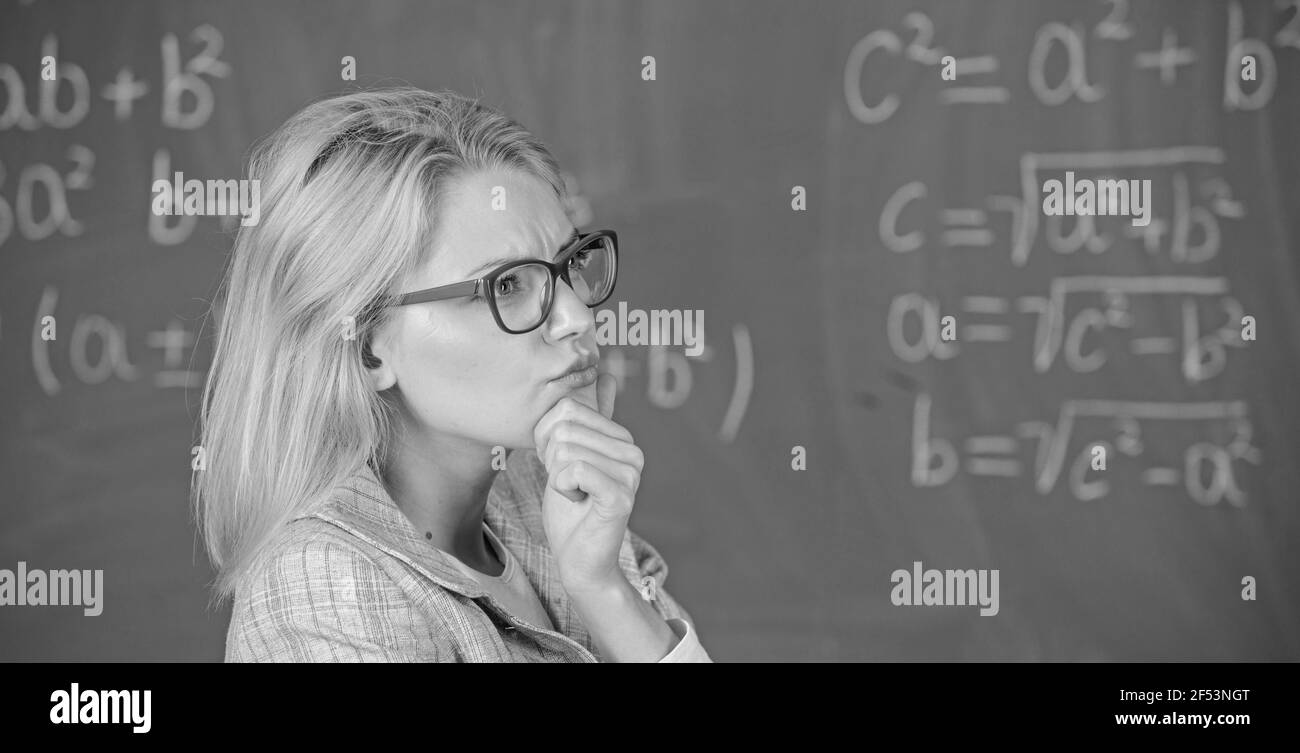 Résoudre la tâche mathématique. Résolvez cette tâche. Éducation scolaire connaissances de base. Une femme enseignante pense à la résolution et au résultat. Lady Wear lunettes élégant Banque D'Images