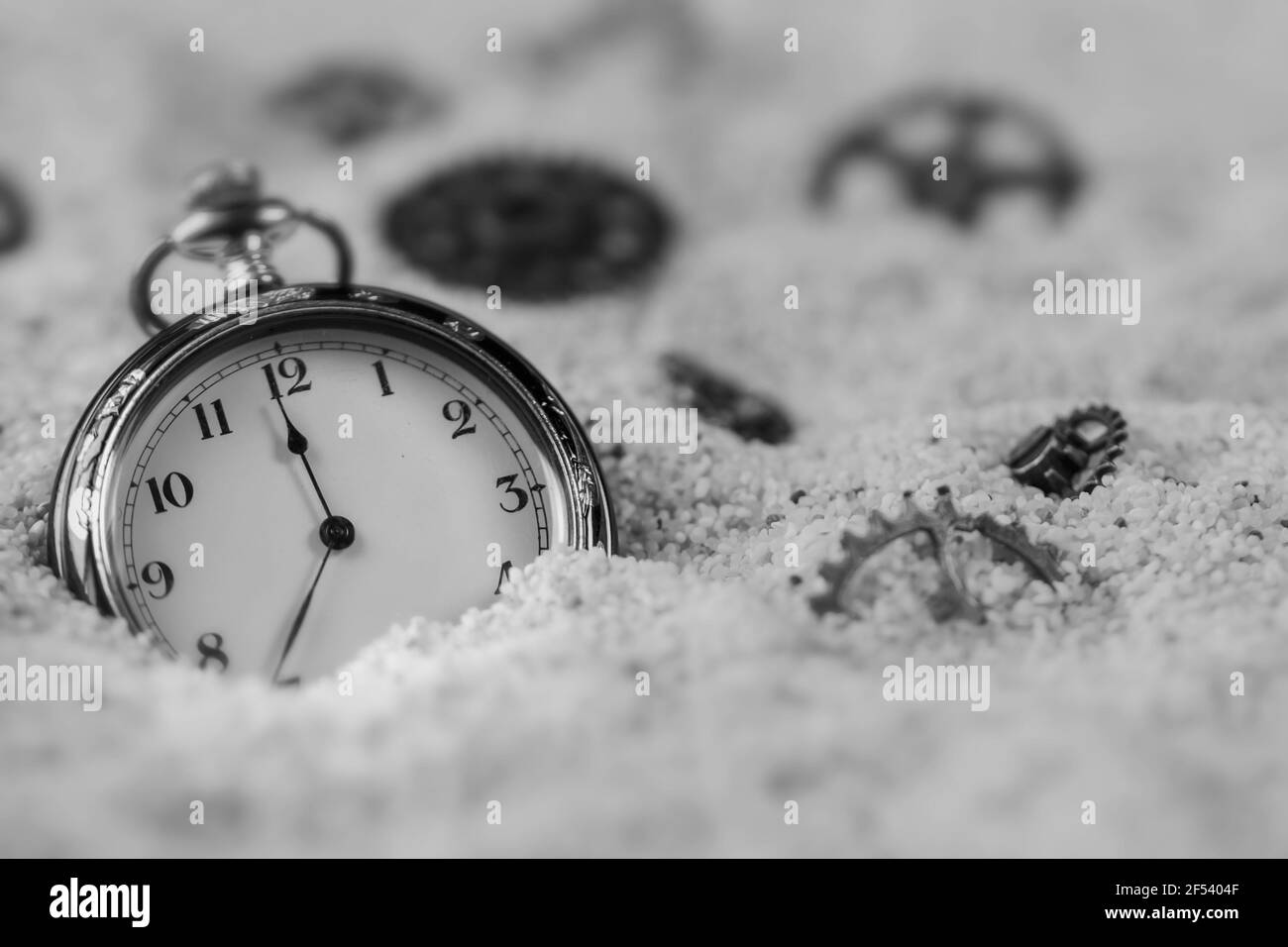 Photographie macro d'une ancienne montre de poche noire et or Sur sable et Steampunk engrenages bronze en métal Banque D'Images