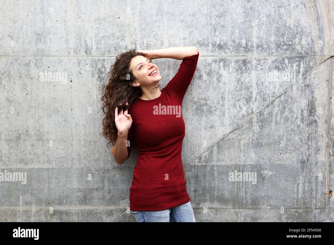 Portrait d'une jeune femme heureuse debout contre un mur gris Banque D'Images