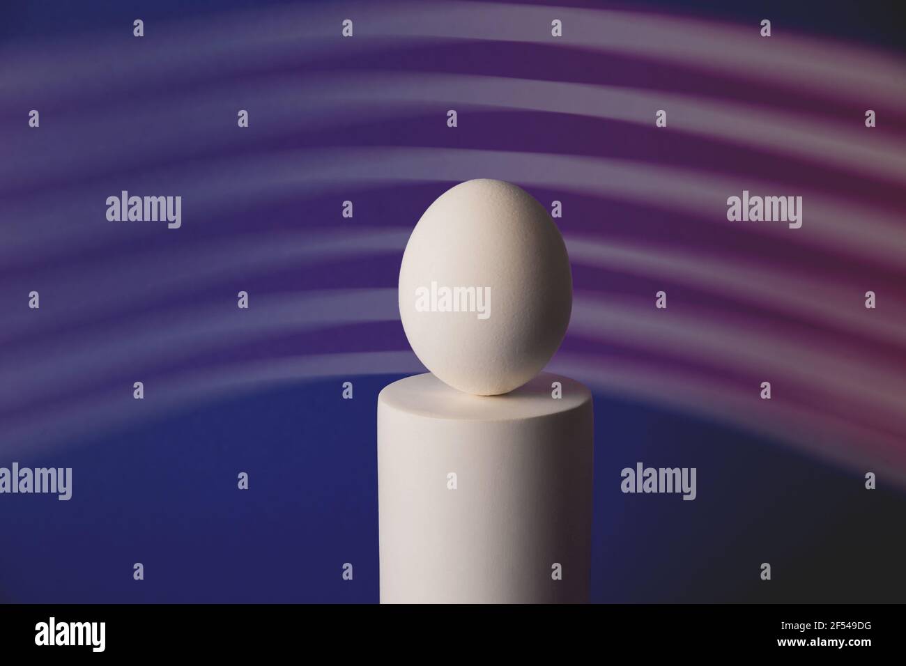 Œuf de pâques blanc sur le podium dans une lumière de néon et de pourpre Banque D'Images