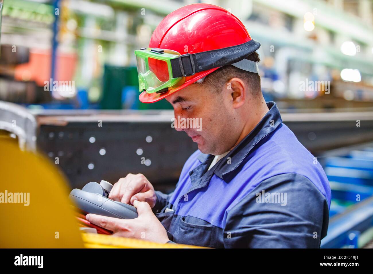 Ekibastuz, région de Pavlodar, Kazakhstan: Usine de construction automobile. Travailleur asiatique en casque rouge et lunettes de protection en plastique programmant machine CNC. Banque D'Images