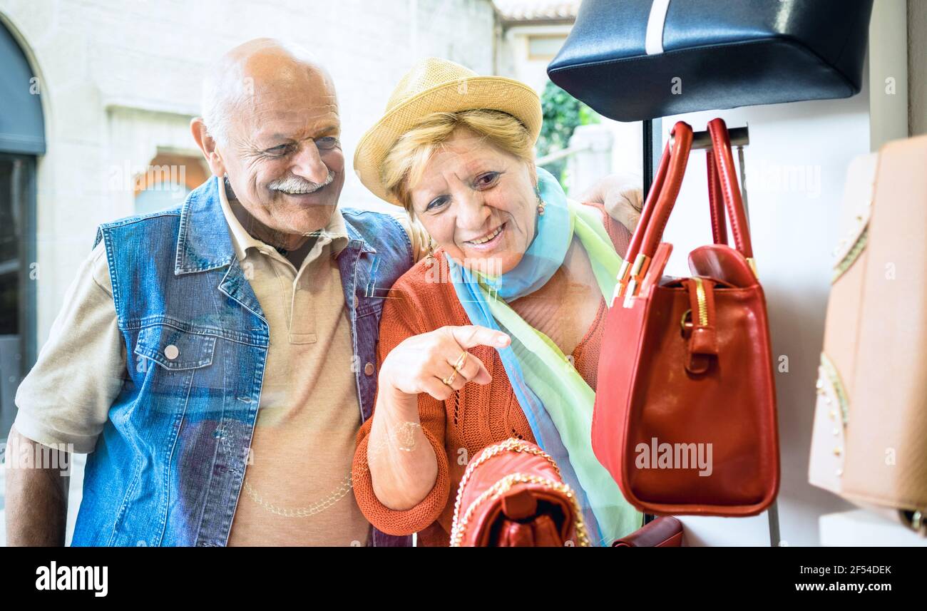 Un couple senior magasinent dans un magasin de sacs mode avec une femme qui pointe Présentation au mari - concept de personnes âgées actives avec homme mature et femme s'amusant Banque D'Images