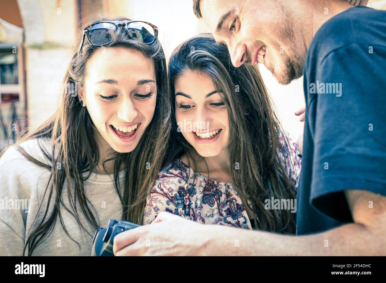 Un homme charmant montre des photos à des filles heureuses et surprises Banque D'Images