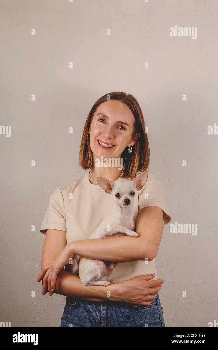 Femme millénaire tenant un petit chien chihuahua dans ses bras à accueil Banque D'Images