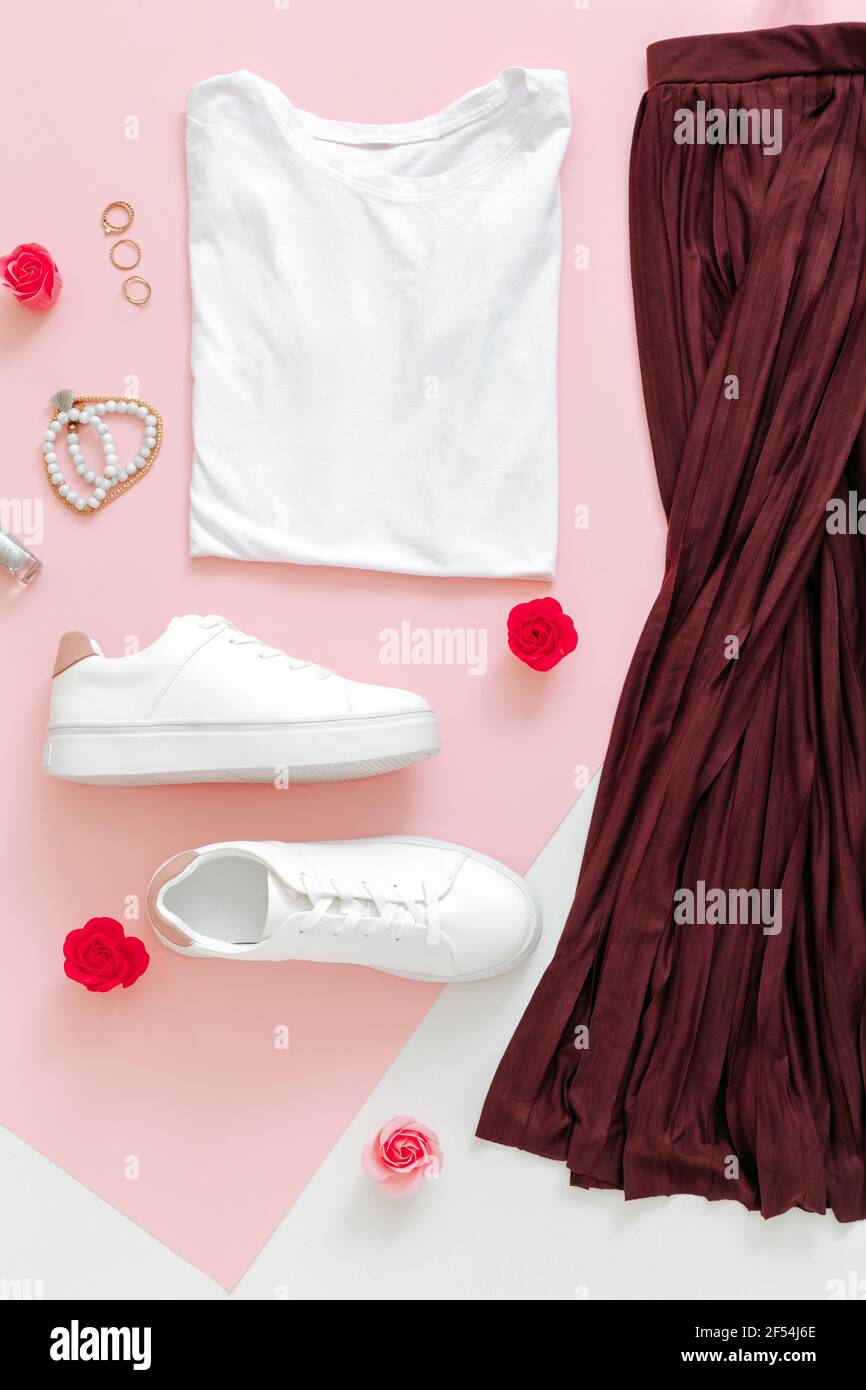 Femme printemps look été tenue jupe chaussures baskets sac tshirt de base. Vêtements pliés pour femmes vêtements de mode urbain ensemble de base avec accessoires fleurs Banque D'Images
