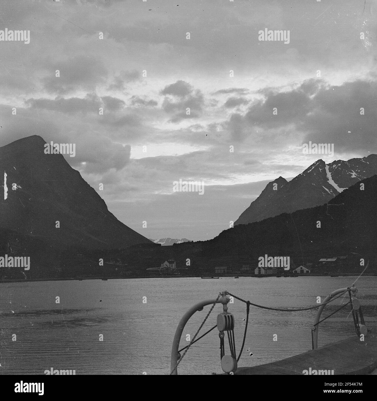 Norvège. Vue depuis un bateau à vapeur pour passagers sur un fjord contre un village avec port de pêche en face des falaises Banque D'Images