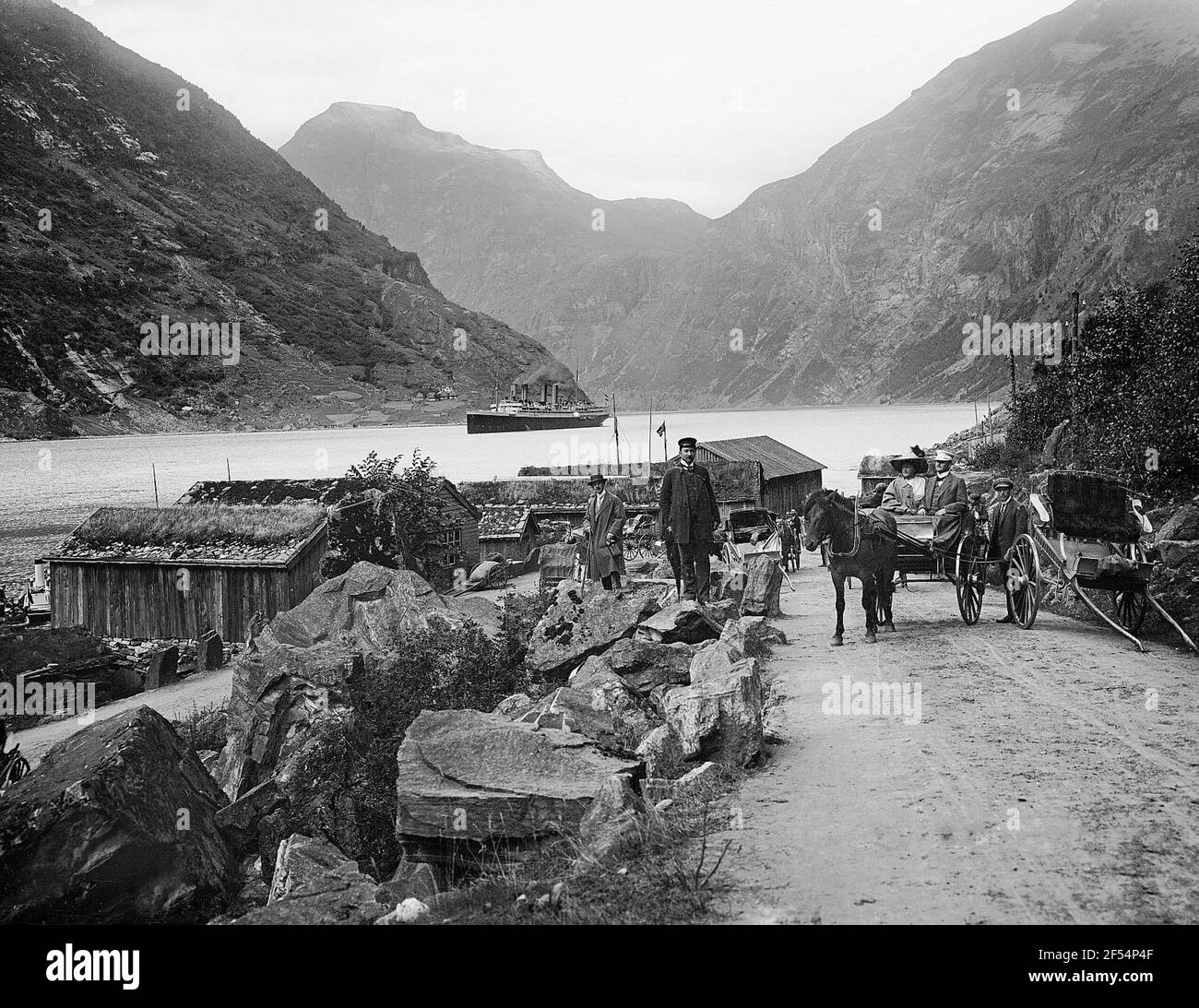 Merok. Vue sur l'emplacement avec les touristes en calèches. Regarder ? À propos de la baie au bateau à vapeur haute mer 'Victoria Luise Merok. Vue sur la partie locale avec les touristes en calèches. Vue sur la baie jusqu'au bateau à vapeur haute mer « Victoria Luise » Banque D'Images